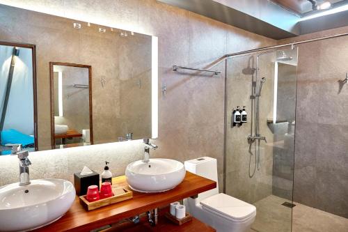 The ANMON Resort Bintan في لاغوي: حمام مع مغسلتين ودش ومرحاض