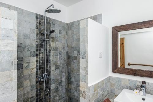 a bathroom with a shower with a sink and a mirror at Happy Days Guest House in Le Morne