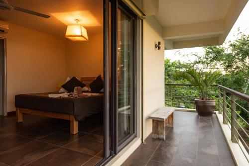 a room with a bed and a balcony at Happy Days Guest House in Le Morne