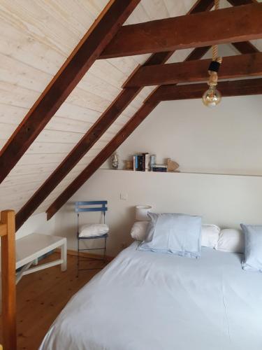 a bedroom with a white bed and a blue chair at penty vero in Plobannalec-Lesconil