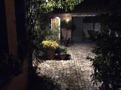 a stone courtyard with potted plants in front of a house at Poortbossen in Zottegem