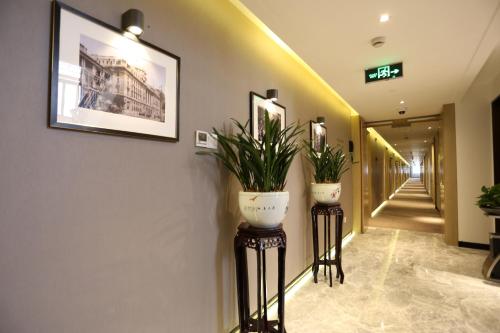 a hallway with two potted plants on pedestals in a building at Jinjiang Metropolo Hotel Classic Nanjing Road (East) Shanghai in Shanghai