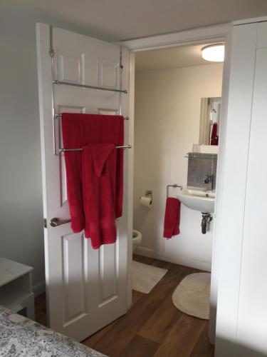a bathroom with red towels hanging on a door at Little Owl Self Catering in Little Barningham