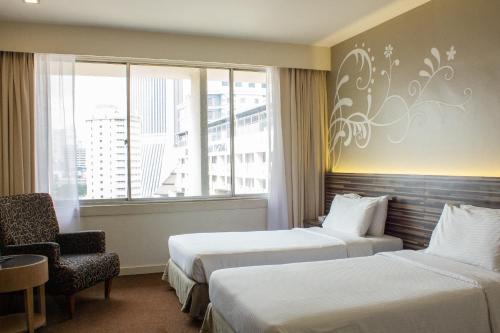um quarto de hotel com duas camas e uma cadeira e uma janela em The 5 Elements Hotel Chinatown Kuala Lumpur em Kuala Lumpur