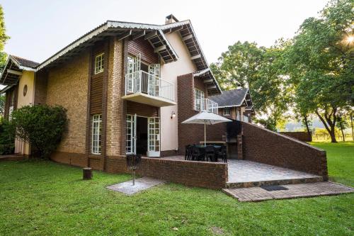 a brick house with a patio in the yard at Merry Pebbles Resort in Sabie