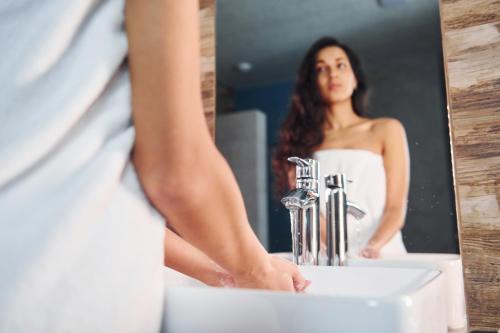 a woman standing in front of a bathroom mirror at Globus Hotel in Ternopilʼ