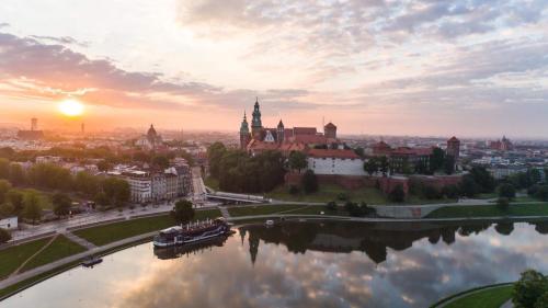 a view of a city with the sun setting over a river at Riverside Aparthotel Cracow in Kraków