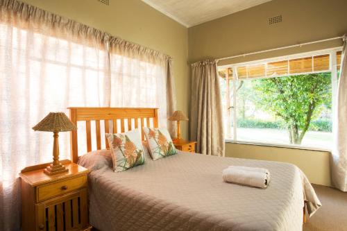 a bedroom with a bed and a large window at Merry Pebbles Resort in Sabie