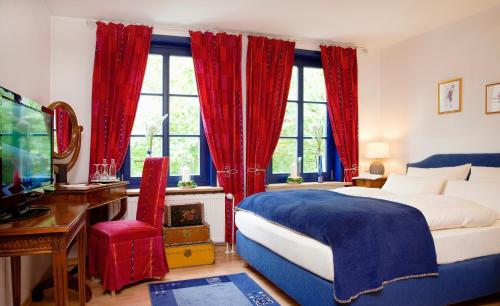 a bedroom with a bed with red curtains and a tv at Landhaus Artischocke in Hemmingen