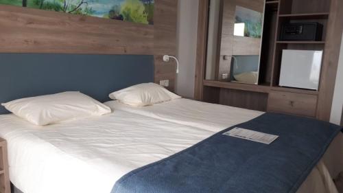 a bed with a blue headboard and white sheets and pillows at Karousos Beach Rooms in Ayia Napa