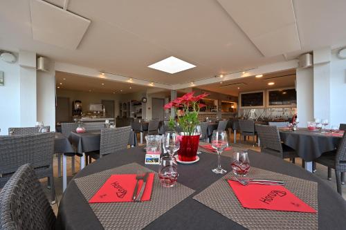 une salle à manger avec des tables, des chaises et des serviettes rouges dans l'établissement Logis Hotel Horus Restaurant Les Bruyeres, à Langon