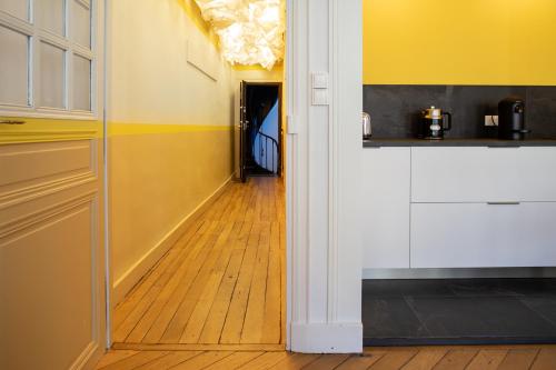 a kitchen with yellow walls and a wooden floor at Maison Tillot in Dijon
