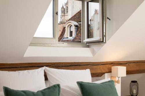 a bedroom with a window above a bed with pillows at Maison Tillot in Dijon