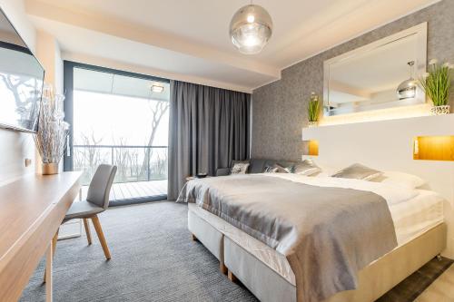 a hotel room with a large bed and a desk at Apartamenty Almar Seaside Park Private in Kołobrzeg