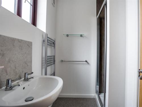ein weißes Bad mit einem Waschbecken und einer Dusche in der Unterkunft New Boathouse in Weymouth