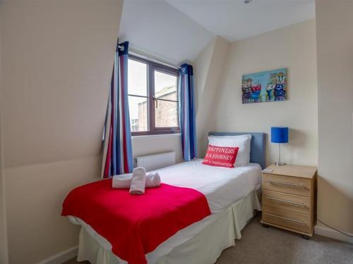 una camera da letto con un letto con una coperta rossa e una finestra di New Boathouse a Weymouth