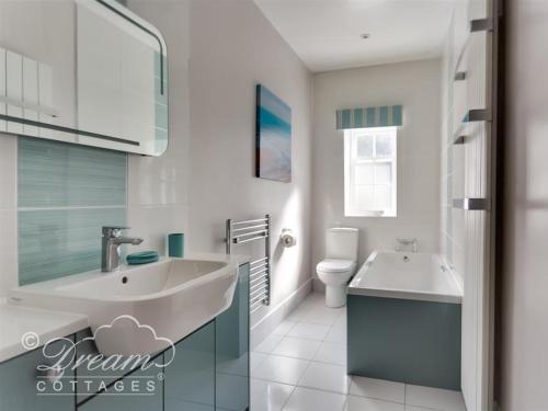 a white bathroom with a sink and a toilet at Safe Harbour in Weymouth