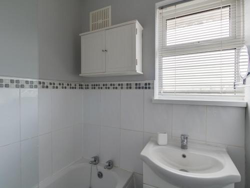 une salle de bain blanche avec un lavabo et une baignoire dans l'établissement The Lookout -The House With A View, à Weymouth