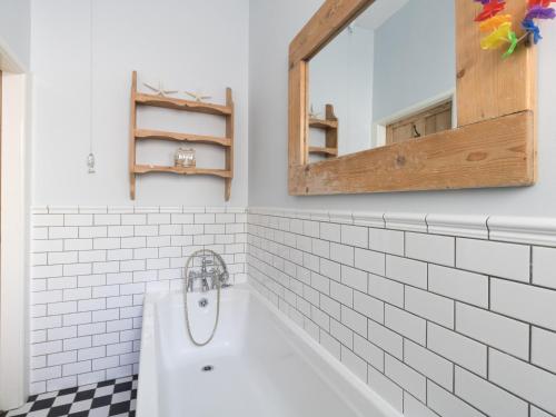 a bathroom with a white tub and a mirror at Sailor's Watch in Weymouth