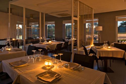 Mon Rêve Resort في تارانتو: مطعم بطاولات بيضاء وكراسي ونوافذ