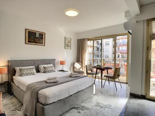 une chambre avec un grand lit et une table et des chaises dans l'établissement Nestor&Jeeves - BERLIOZ SUITE - Downtown - Close beaches, à Nice