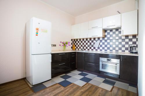 a kitchen with a white refrigerator and black cabinets at Apartment near Obolon metro station in Kyiv