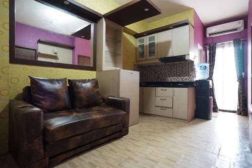 Una sala de estar con un sofá de cuero y una cocina. en Planet Room Kemang View, en Pekayon Satu