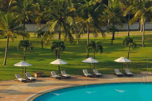 a group of chairs and umbrellas next to a pool at Mövenpick Ambassador Hotel Accra in Accra