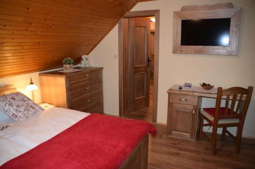 a bedroom with a bed and a desk with a television at Farm Stay "Alpine Dreams" in Solčava