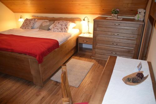 a bedroom with a bed and a dresser and a table at Farm Stay "Alpine Dreams" in Solčava