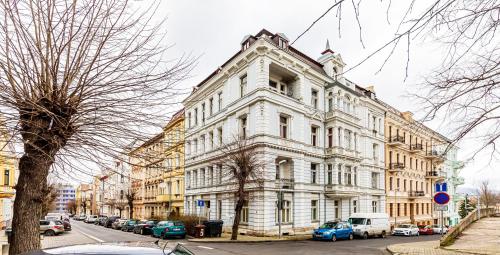 a large white building with cars parked on a street at Teplice Apartments U Schodů in Teplice