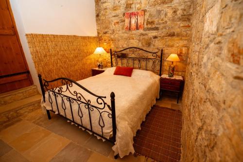 a bedroom with a bed in a stone wall at Constantias stone houses in Lofou