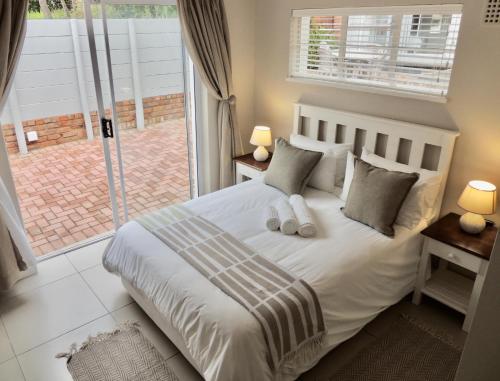 a bedroom with a white bed with pillows and a window at La Mer Guesthouse in Port Elizabeth