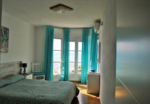 リンコン・デ・ラ・ビクトリアにあるAPARTAMENTO FRENTE AL MAR,PRIMERA LINEA DE PLAYAのベッドルーム1室(ベッド1台、青いカーテン付きの窓付)