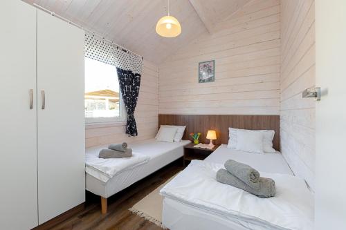 two beds in a room with wooden walls at Chłopy Beach Resort in Chłopy