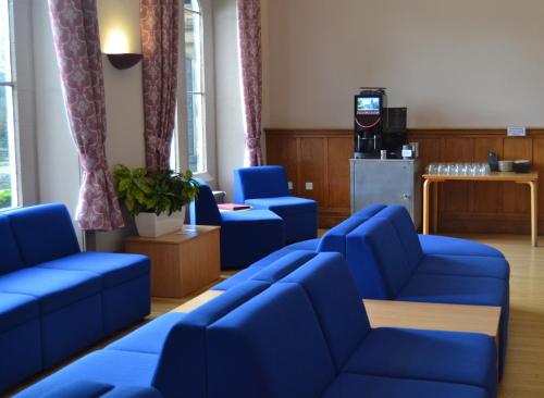 a waiting room with blue chairs and a television at Hinsley Hall in Leeds