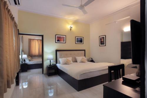 a bedroom with two beds and a television in it at Mimosa Udaipur in Udaipur