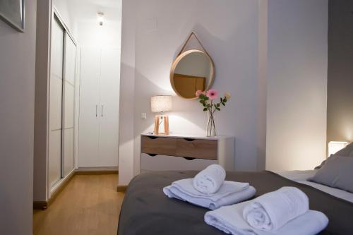 a bedroom with a bed with towels and a mirror at Luz y Tranquilidad en el Casco Histórico - Parking Gratis in Seville