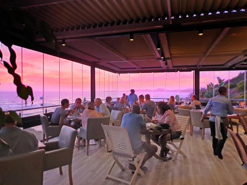 a group of people sitting at tables in a restaurant at Brenton Haven Beachfront Resort in Knysna