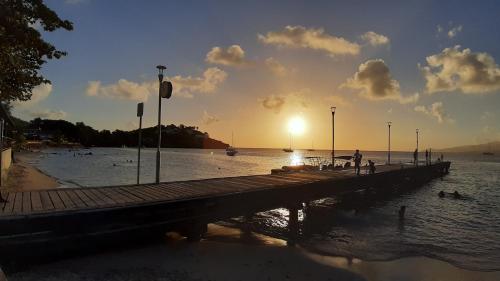 a pier with the sun setting over the water at akate in Les Trois-Îlets