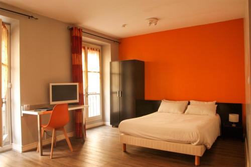 um quarto com uma parede laranja, uma cama e uma secretária. em Avy Residence Lyon Bellecour em Lyon