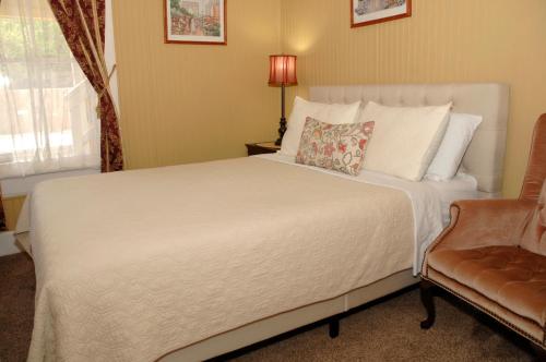 a bedroom with a large white bed and a chair at Quaint Historic Downtown Apartment in St. Augustine