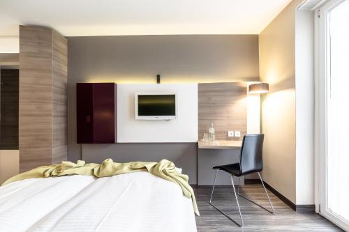 a bedroom with a bed and a tv on the wall at Hotel Demas City in Munich