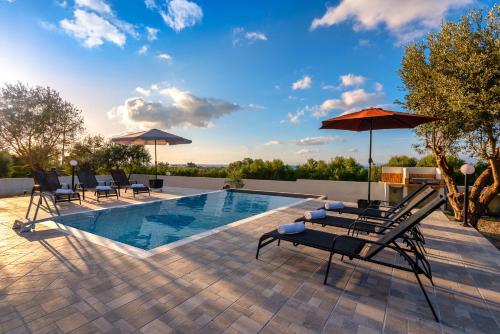 a pool with chairs and umbrellas on a patio at Vasilis Villa in Fánai