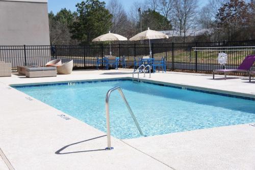 a swimming pool with a metal fence and chairs and umbrellas at La Quinta Inn & Suites by Wyndham Braselton in Braselton