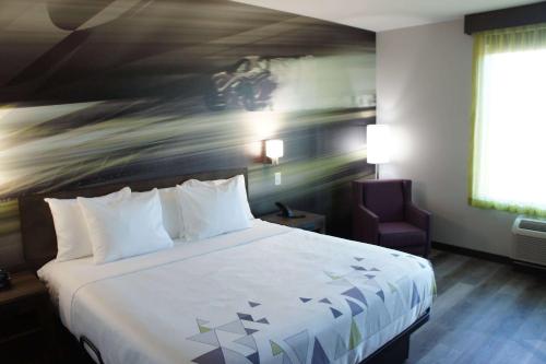 a hotel room with a large bed and a chair at La Quinta Inn & Suites by Wyndham Braselton in Braselton