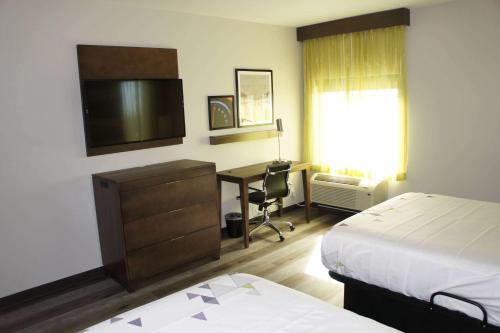 a hotel room with a bedroom with a desk and a bed at La Quinta Inn & Suites by Wyndham Braselton in Braselton