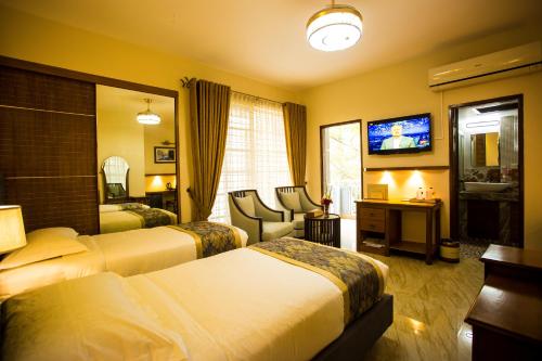 a hotel room with two beds and a television at Shinepukur Suites in Dhaka
