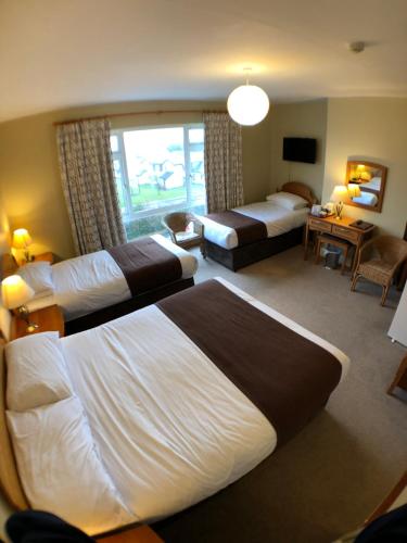 Habitación de hotel con 2 camas y sala de estar. en Beach Haven B&B, en Tramore