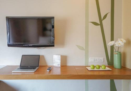 a desk with a laptop and a tv on a wall at The 5 Elements Hotel Chinatown Kuala Lumpur in Kuala Lumpur